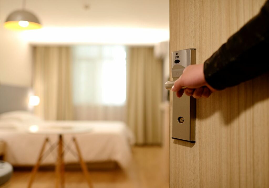 A person opening the door of a hotel room